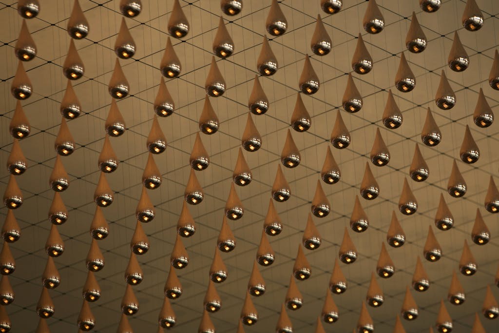 Metallic droplets suspended in an intricate net pattern, creating an immersive art installation.